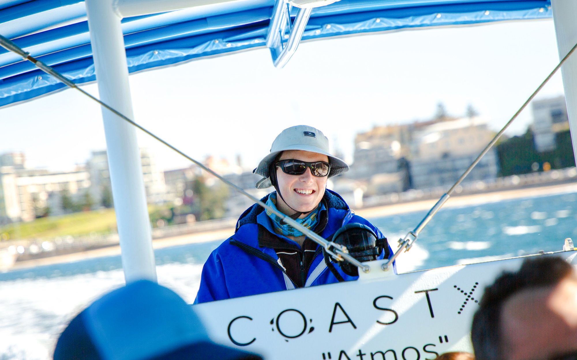 Person enjoying a boat tour in Newcastle with coastal view in the background.