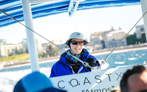 Person enjoying a boat tour in Newcastle with coastal view in the background.