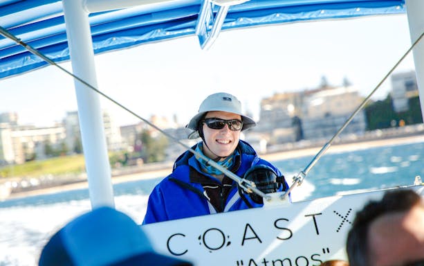 Person enjoying a boat tour in Newcastle with coastal view in the background.