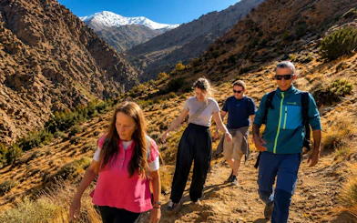 Hikers exploring Ourika Valley in Atlas Mountains, Marrakech, with snow-capped peaks in the background.