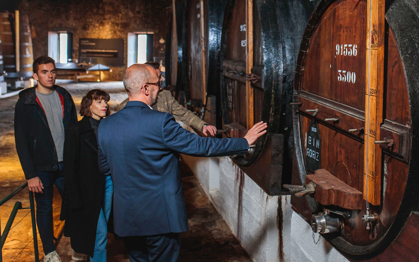 Visitors exploring large wine barrels at Fonseca Port Wine Cellars in Portugal.