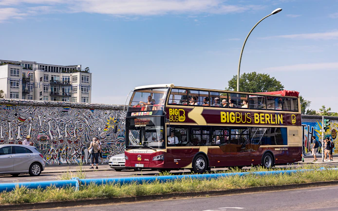 Big Bus Berlin tour passing by the Berlin Wall with colorful murals.
