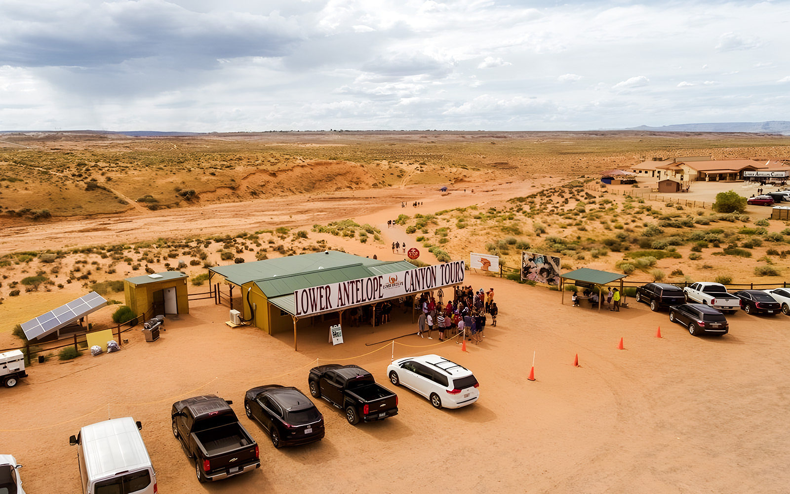 Lower Antelope Canyon tour entrance with visitors gathering in desert landscape.