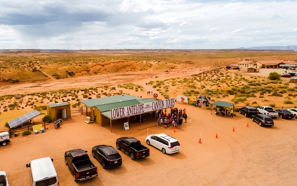 Lower Antelope Canyon tour entrance with visitors gathering in desert landscape.