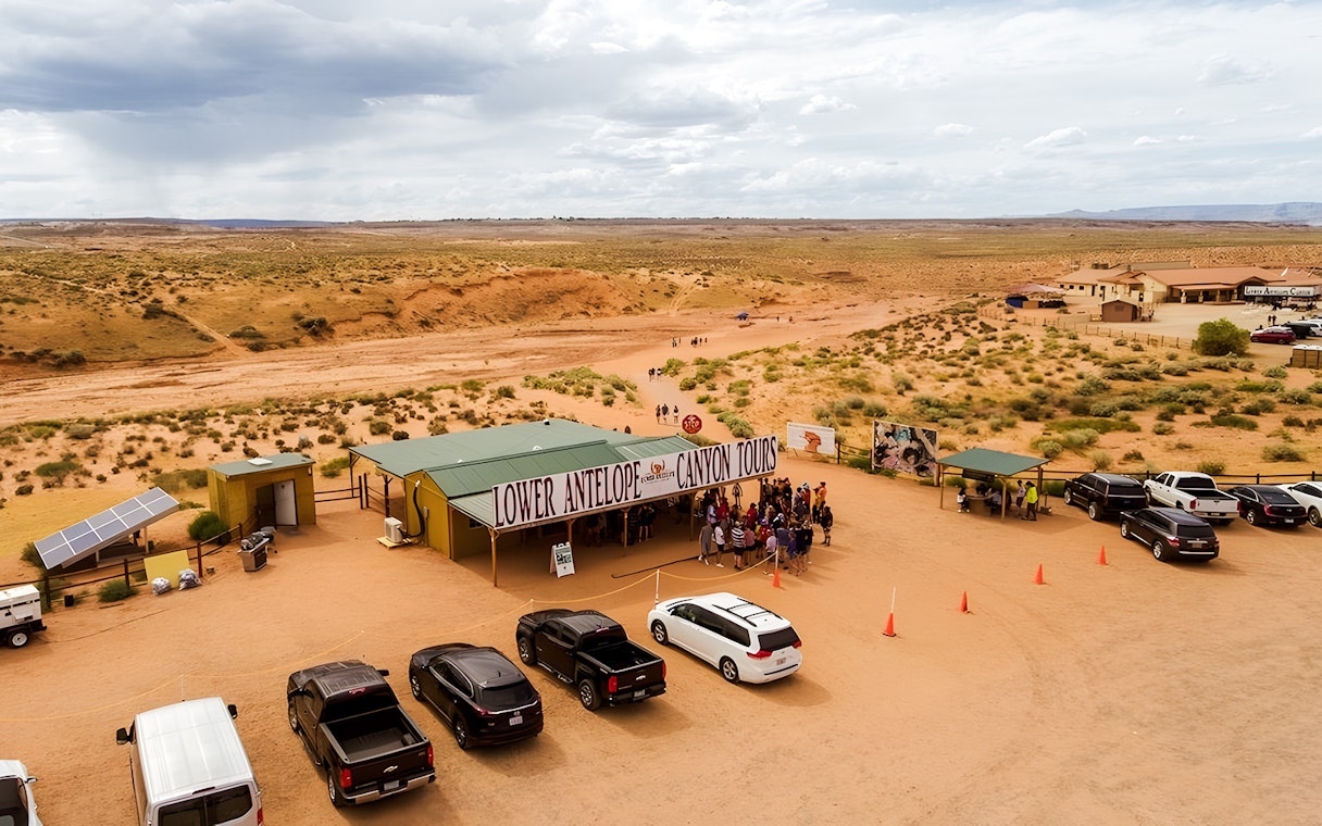 Lower Antelope Canyon tour entrance with visitors gathering in desert landscape.