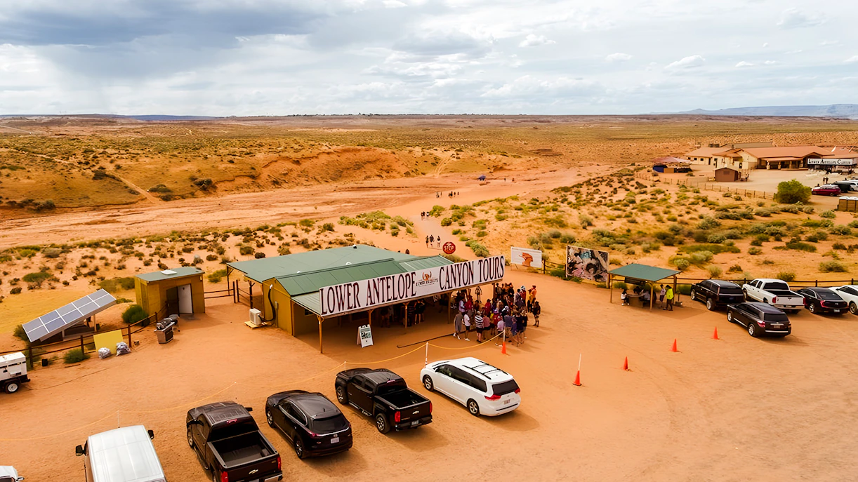 Lower Antelope Canyon tour entrance with visitors gathering in desert landscape.
