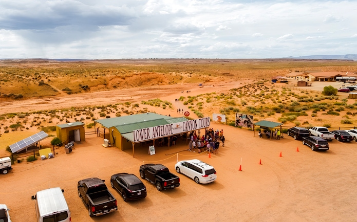 Lower Antelope Canyon tour entrance with visitors gathering in desert landscape.
