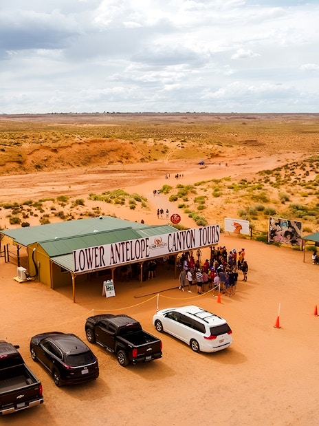 Lower Antelope Canyon tour entrance with visitors gathering in desert landscape.