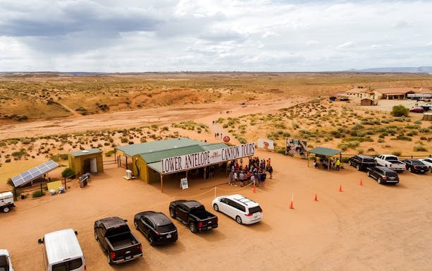 Lower Antelope Canyon tour entrance with visitors gathering in desert landscape.