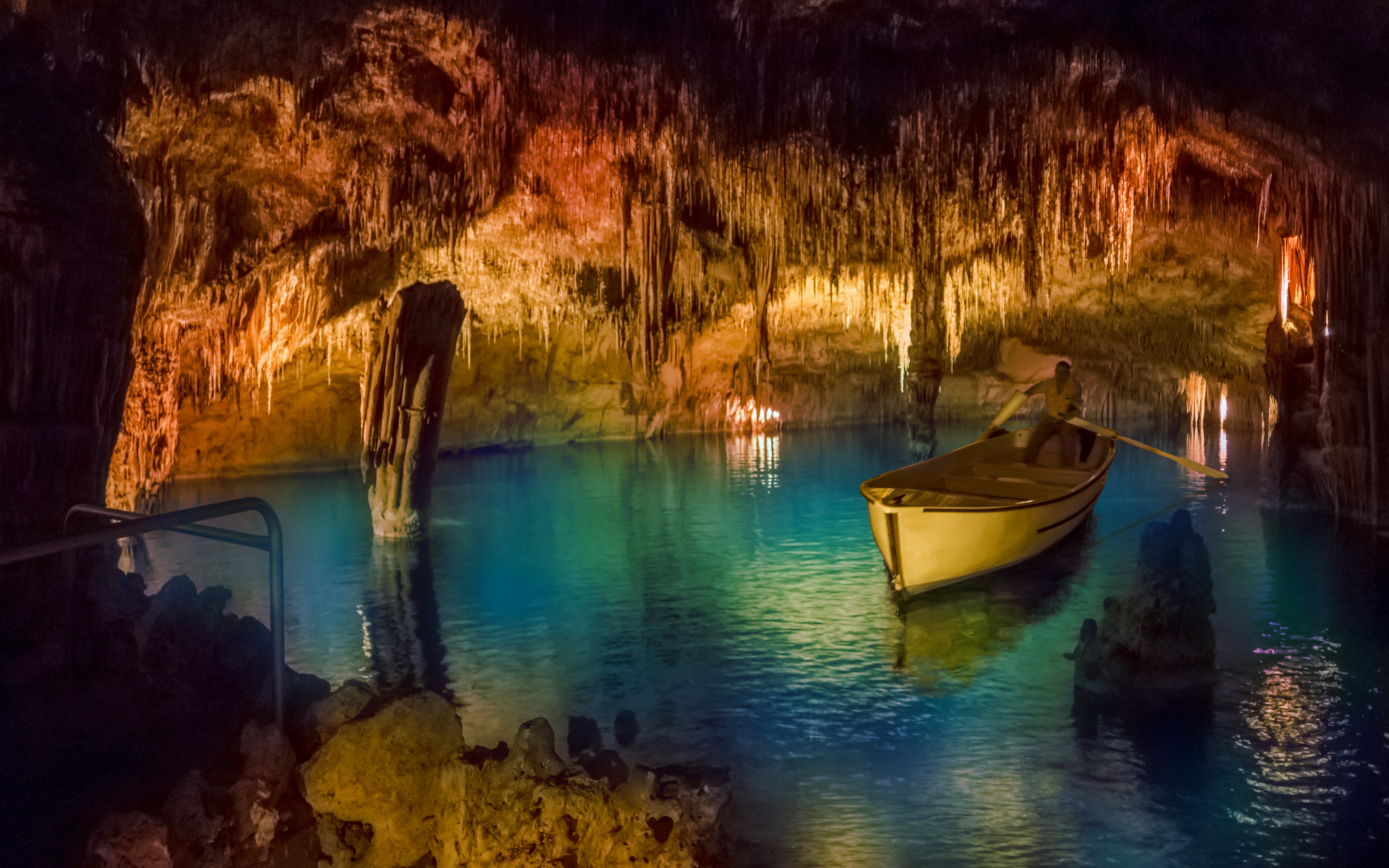 Boat tour inside Drach Caves with illuminated stalactites and turquoise water.