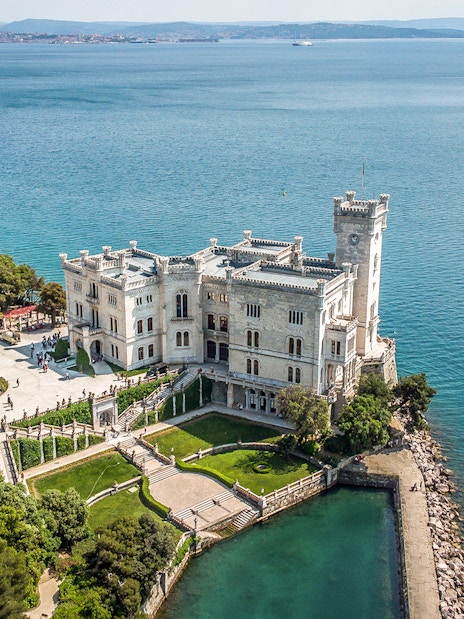Miramare Castle overlooking the Gulf of Trieste, surrounded by gardens and sea.