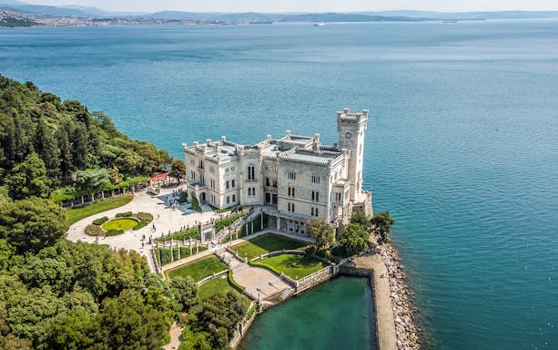 Miramare Castle overlooking the Gulf of Trieste, surrounded by gardens and sea.