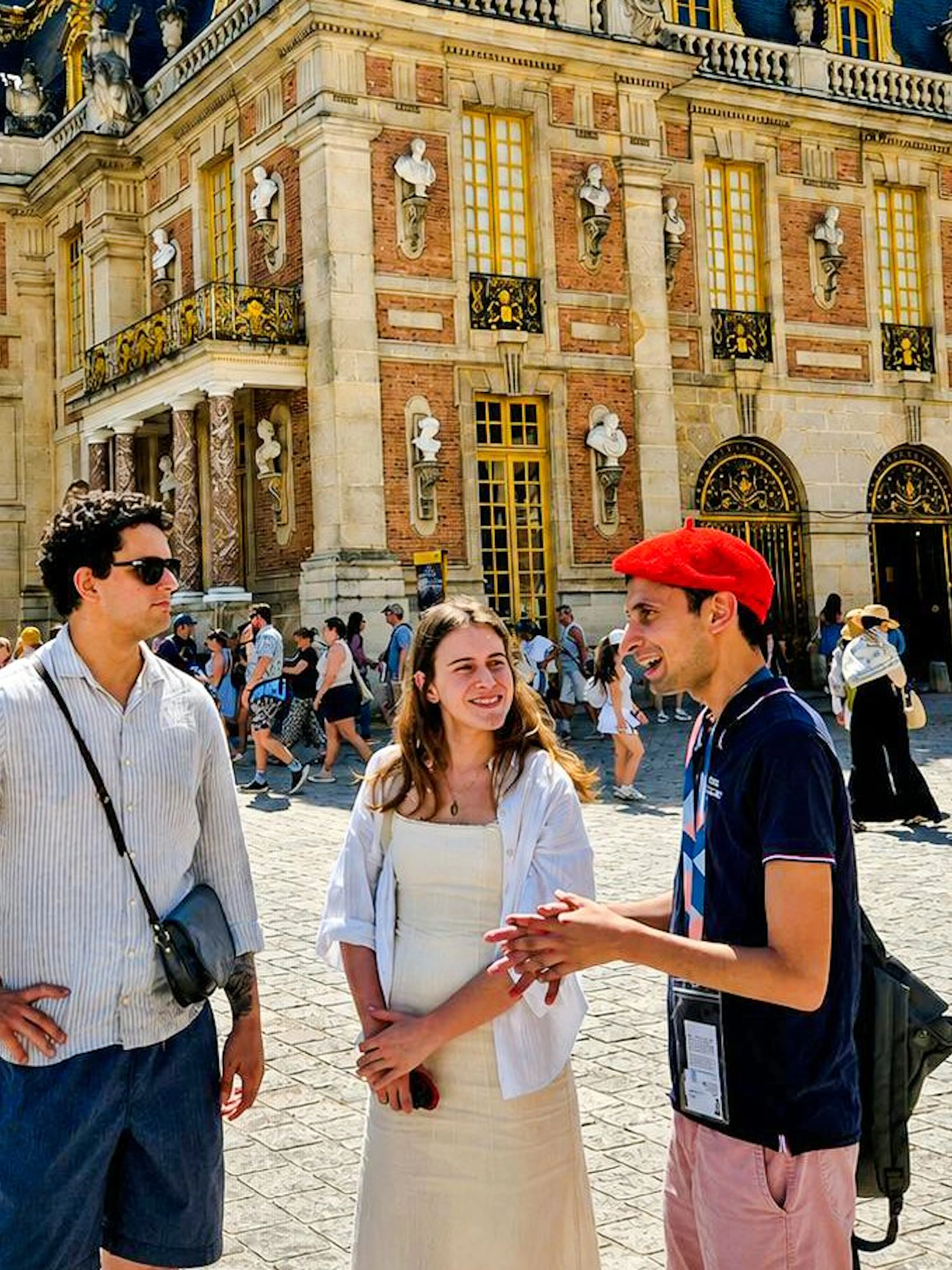 Tour guide with visitors at Versailles Palace entrance, France.
