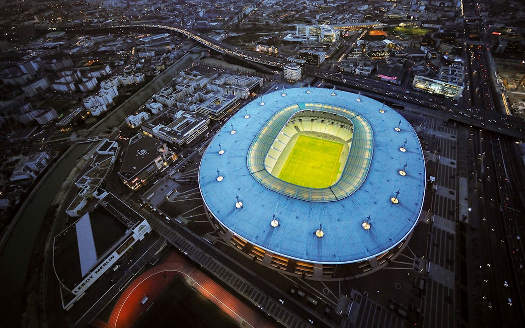 Aerial view of Stade de France in Saint-Denis, Paris, illuminated at night.