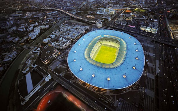 Aerial view of Stade de France in Saint-Denis, Paris, illuminated at night.