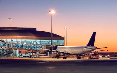 Airplane at London City Airport gate during sunset.