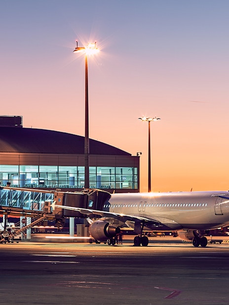 Airplane at London City Airport gate during sunset.