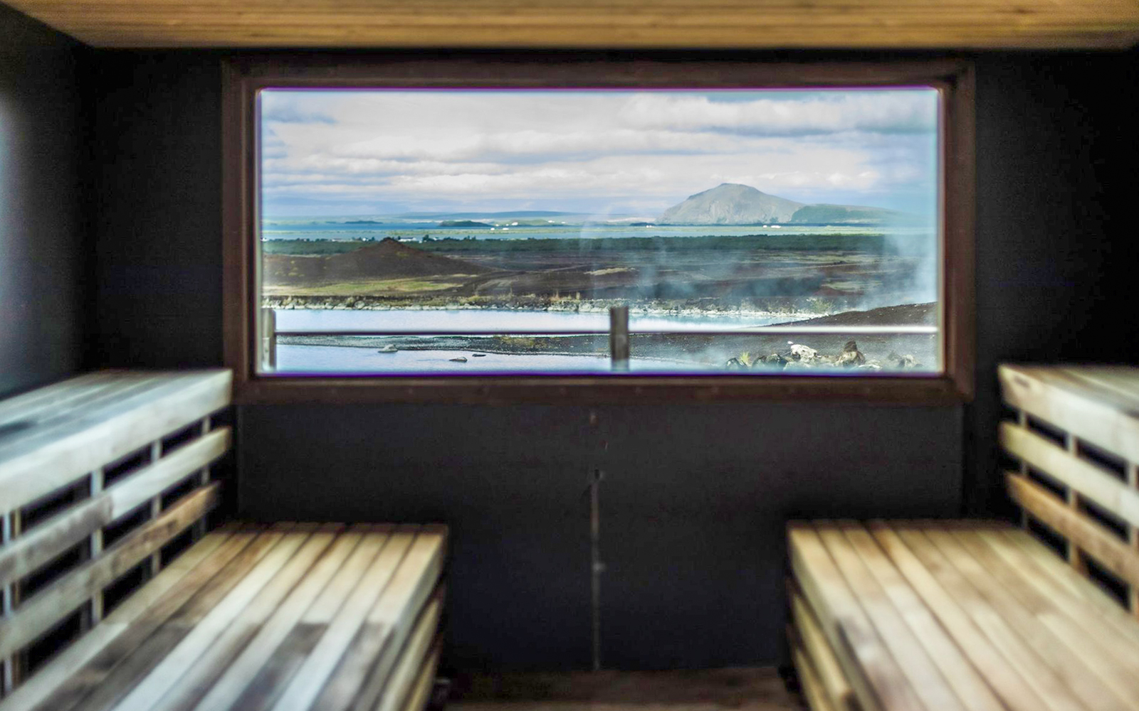 Sauna interior with view of Myvatn Nature Baths and Icelandic landscape.
