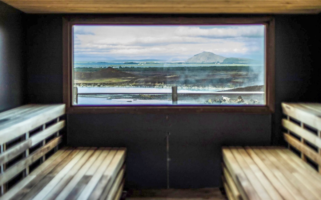 Sauna interior with view of Myvatn Nature Baths and Icelandic landscape.