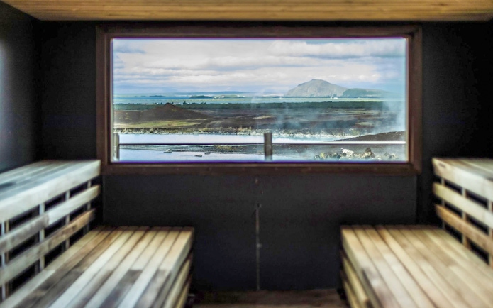 Sauna interior with view of Myvatn Nature Baths and Icelandic landscape.