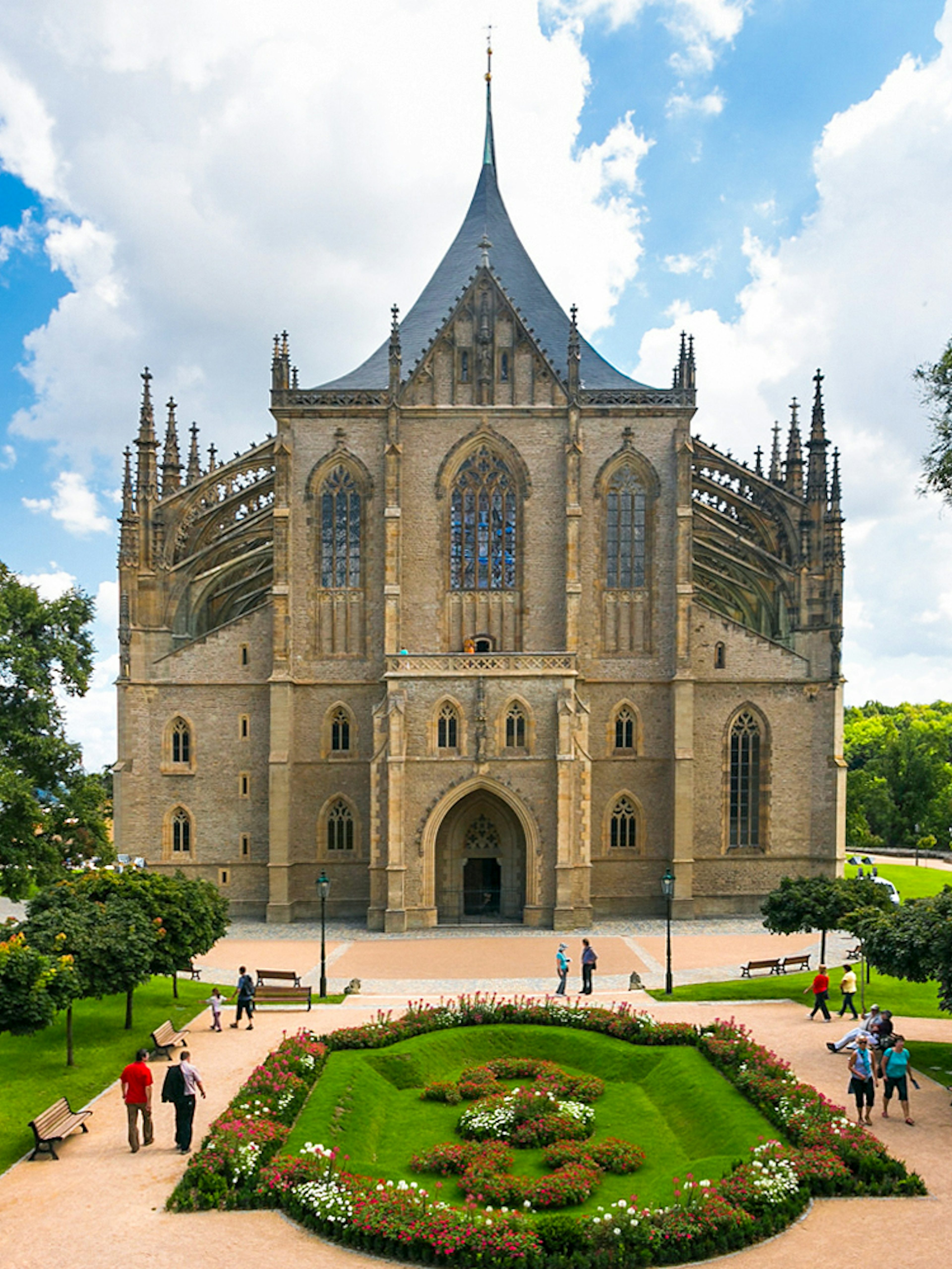 St. Barbara's Church in Kutna Hora with surrounding gardens and visitors.