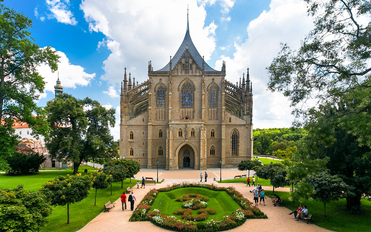 St. Barbara's Church in Kutna Hora with surrounding gardens and visitors.