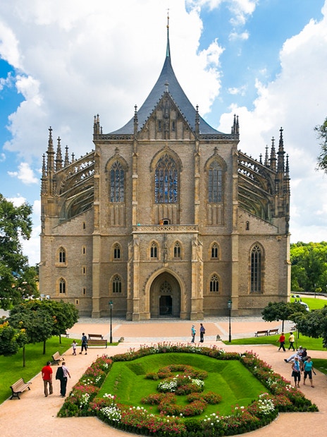 St. Barbara's Church in Kutna Hora with surrounding gardens and visitors.