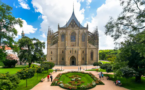 St. Barbara's Church in Kutna Hora with surrounding gardens and visitors.