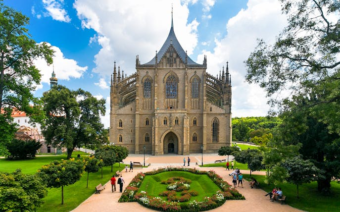 St. Barbara's Church in Kutna Hora with surrounding gardens and visitors.