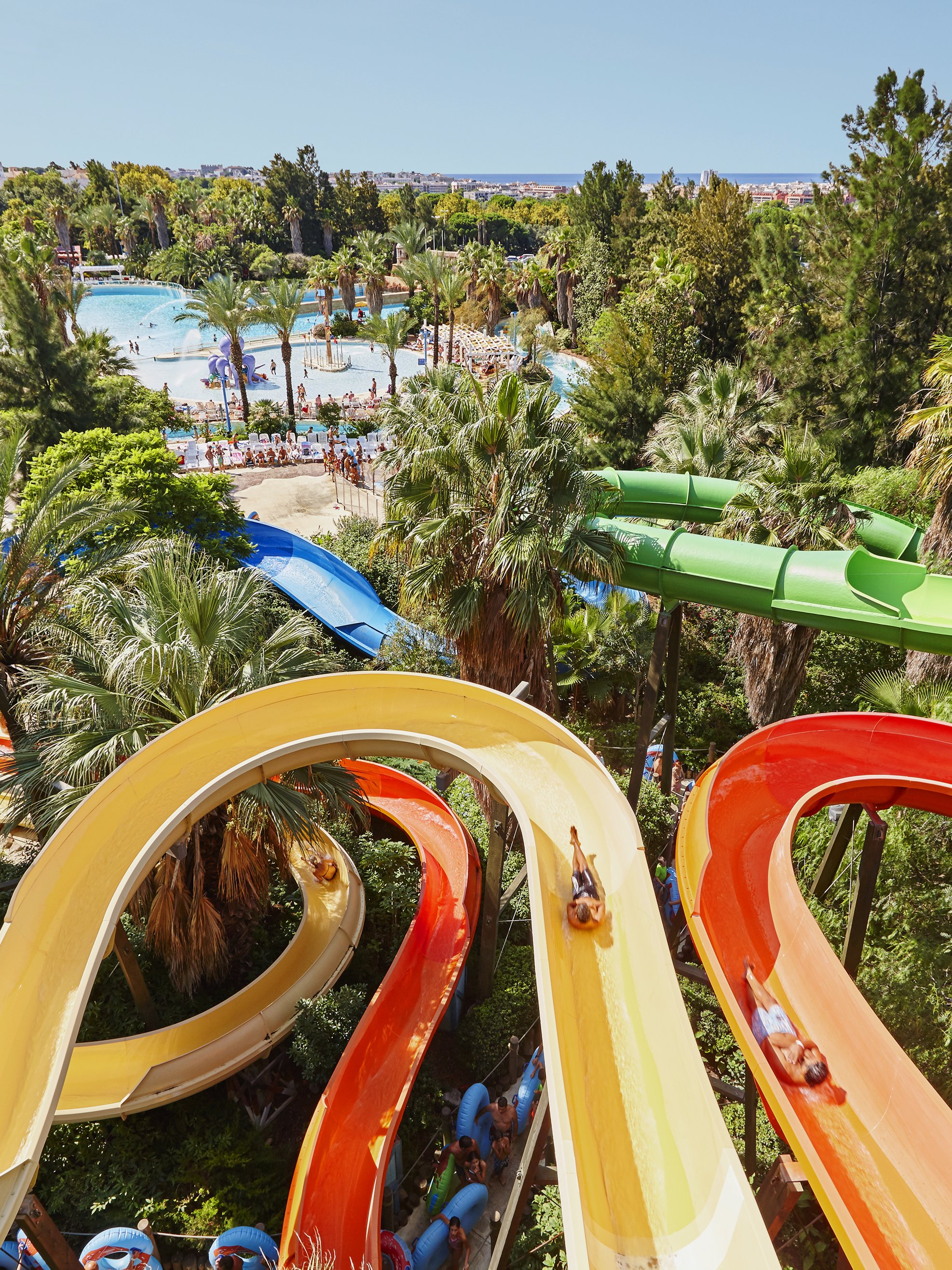 Aerial view of Caribe Aquatic Park with colorful water slides and pools surrounded by lush greenery.