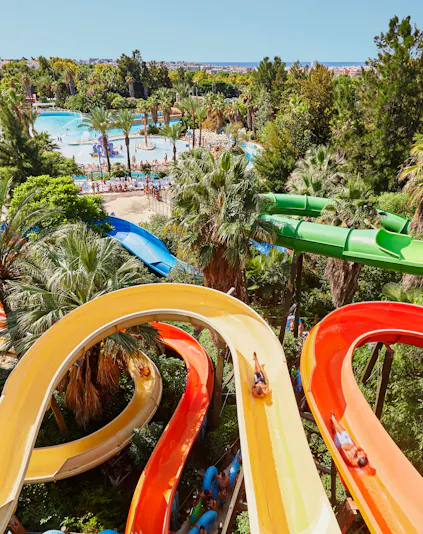 Aerial view of Caribe Aquatic Park with colorful water slides and pools surrounded by lush greenery.