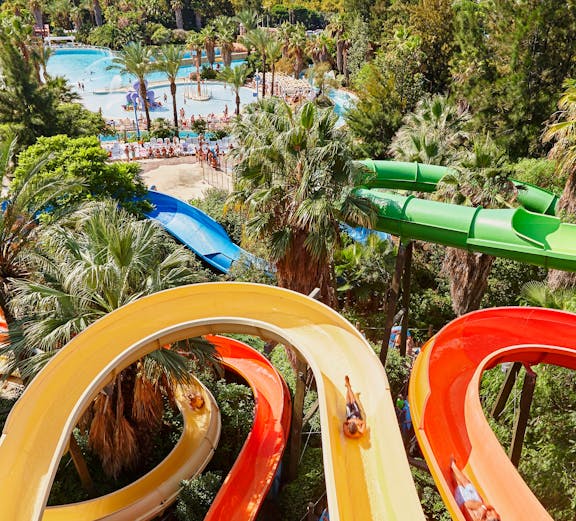 Aerial view of Caribe Aquatic Park with colorful water slides and pools surrounded by lush greenery.