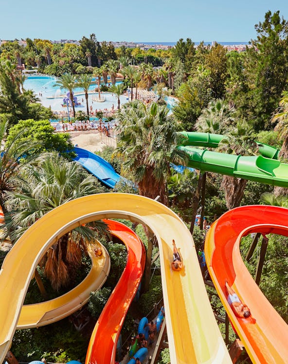 Aerial view of Caribe Aquatic Park with colorful water slides and pools surrounded by lush greenery.