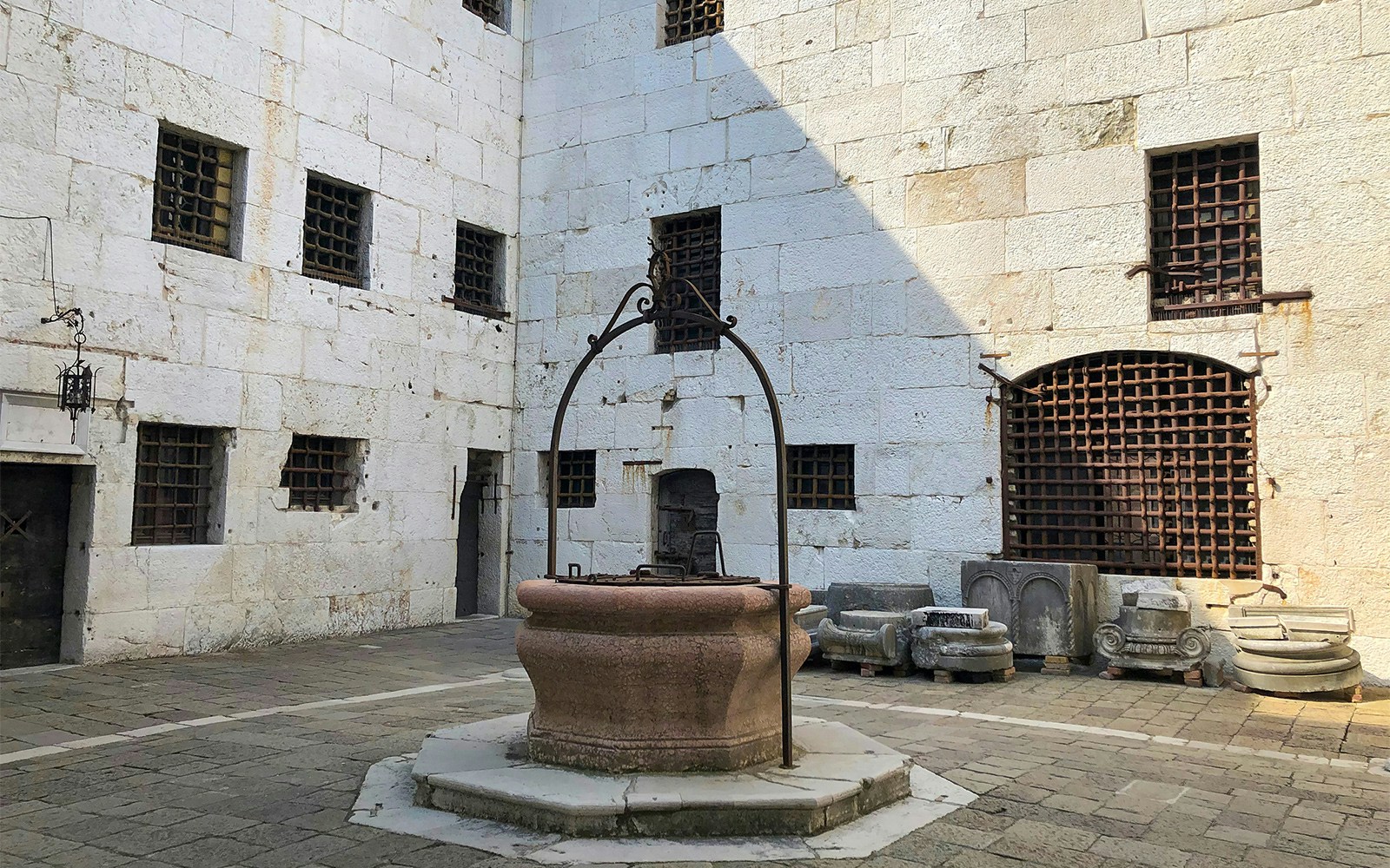 Courtyard of Doge's Palace Prisons with stone well and barred windows, Venice.