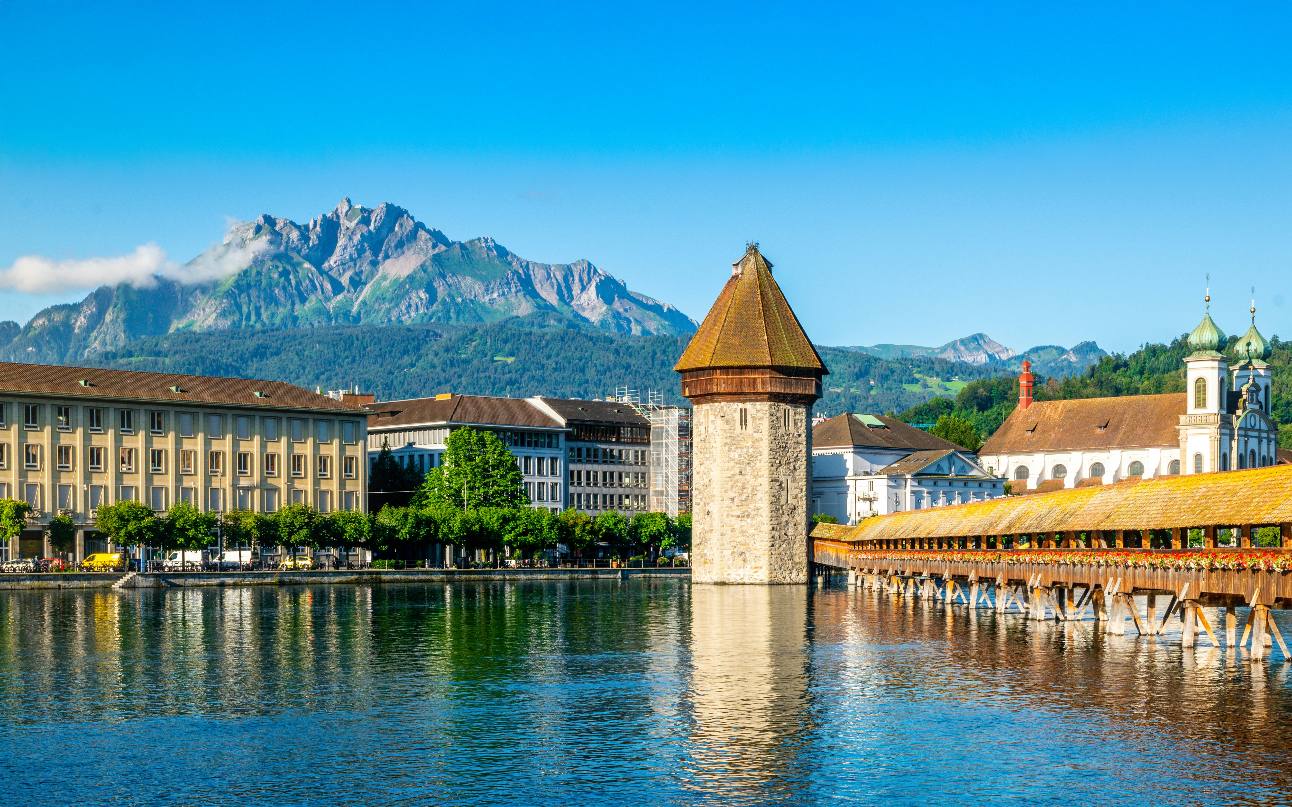 Lucerne's Chapel Bridge and Pilatus Mountain under clear blue sky, Switzerland.