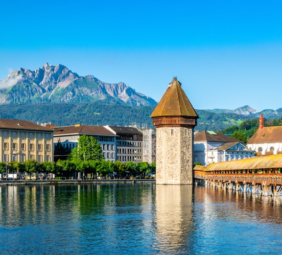 Lucerne's Chapel Bridge and Pilatus Mountain under clear blue sky, Switzerland.