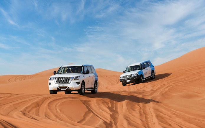 4x4 vehicles driving on sand dunes during Abu Dhabi desert safari.