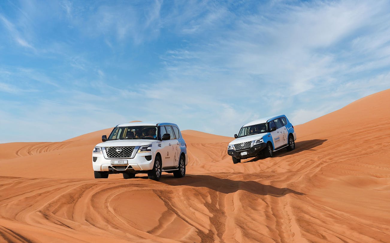 4x4 vehicles driving on sand dunes during Abu Dhabi desert safari.