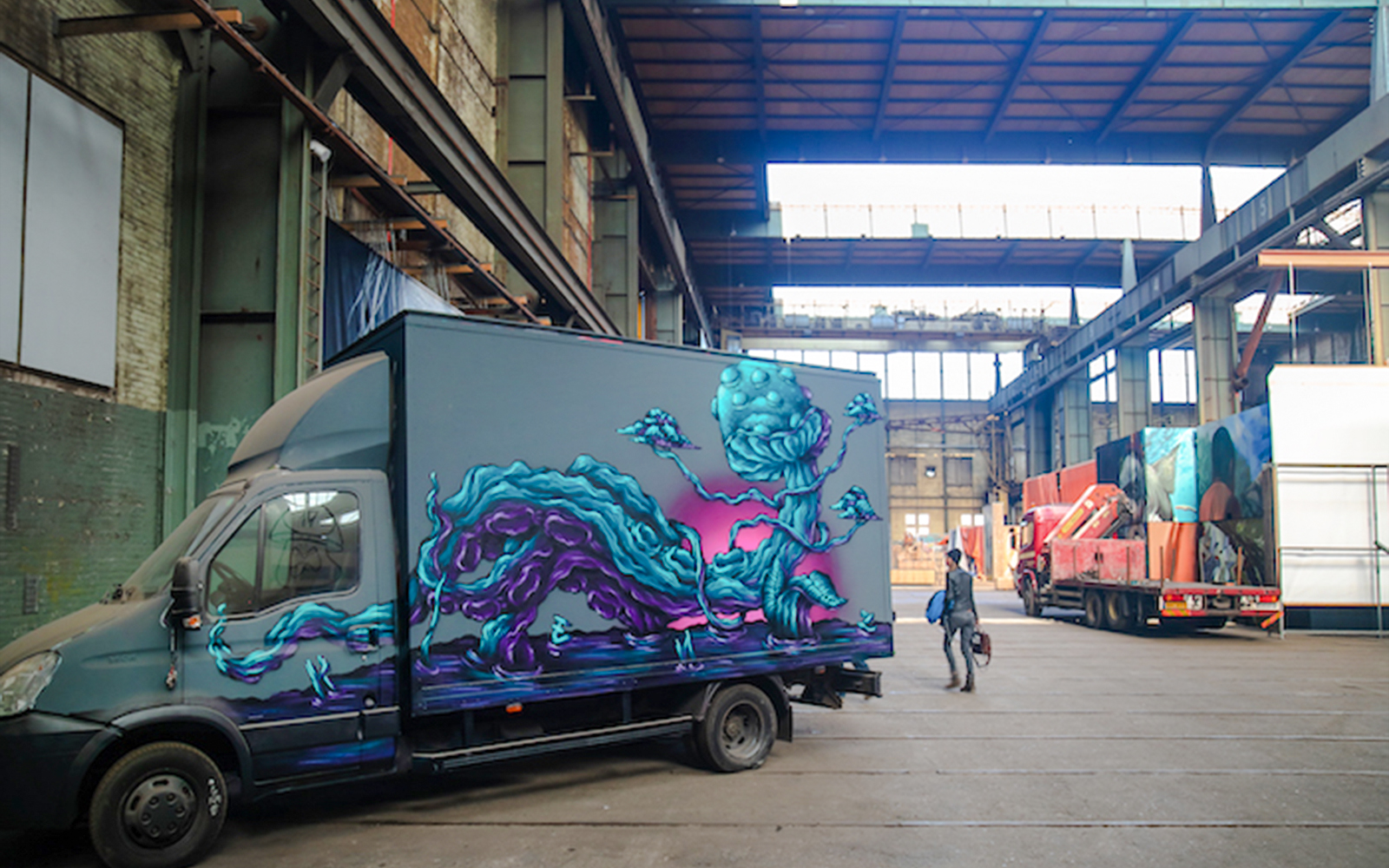 Hanging Truck by Carl KENZ with vibrant mural in an industrial warehouse.