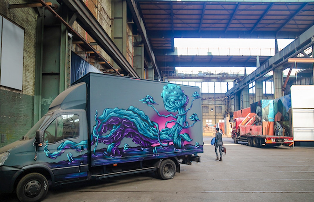 Hanging Truck by Carl KENZ with vibrant mural in an industrial warehouse.