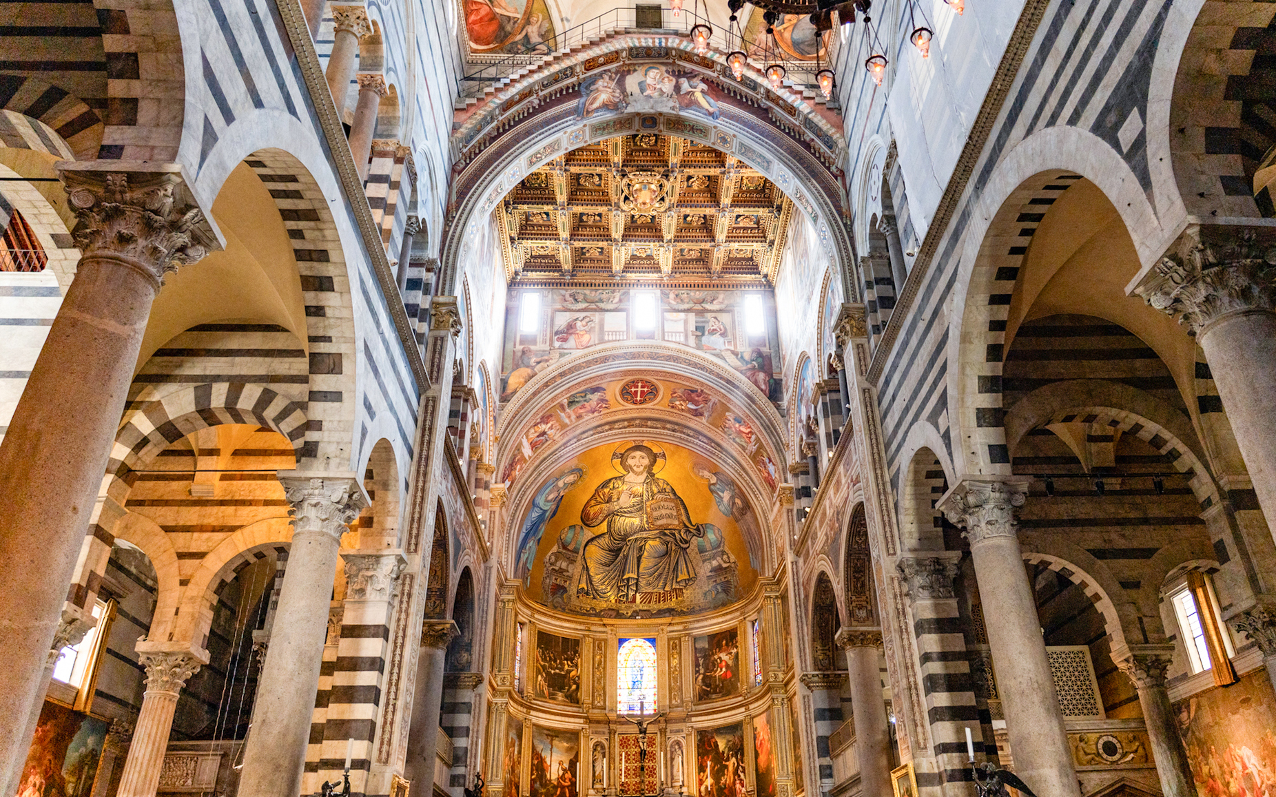Pisa Cathedral interior with ornate ceiling and religious frescoes.