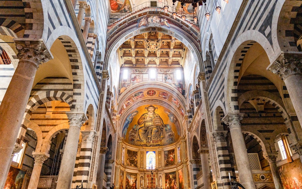 Pisa Cathedral interior with ornate ceiling and religious frescoes.