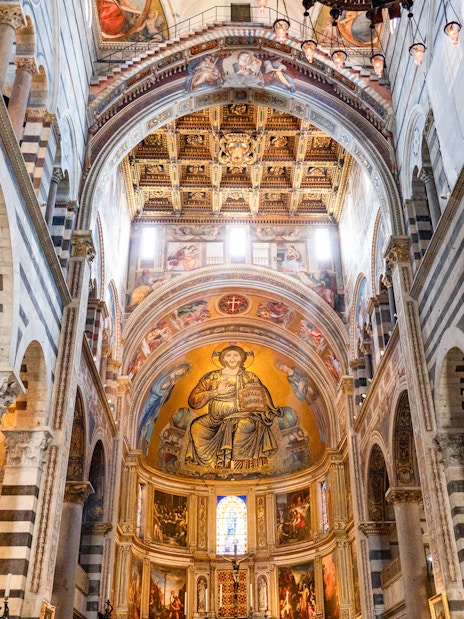 Pisa Cathedral interior with ornate ceiling and religious frescoes.