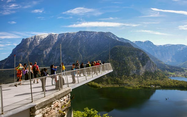 Visitors on a viewing platform overlooking Hallstatt's mountains and lake during a half-day trip from Salzburg.
