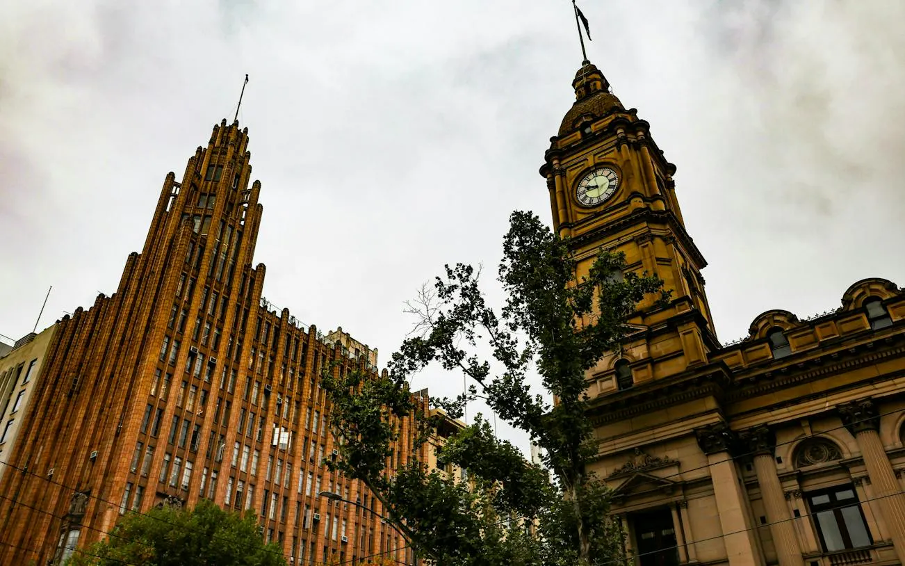 Historic buildings with clock tower in Melbourne cityscape.