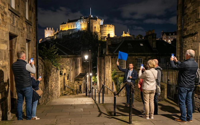 Tour group on Edinburgh True Crime Walking Tour near Edinburgh Castle at night.
