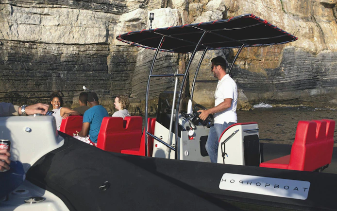 Boat tour near rocky cliffs in Portovenere, La Spezia, with passengers enjoying the view.