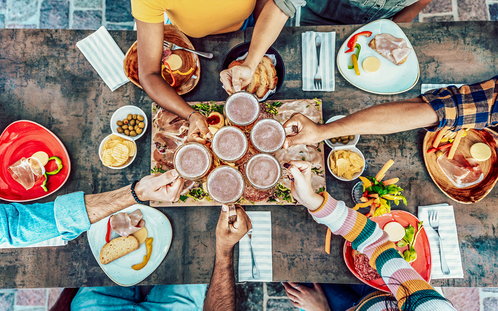 Friends cheering beer glasses at a rustic bar, Genoa