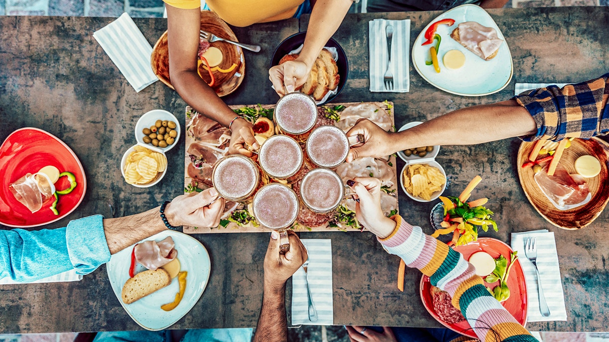 Friends cheering beer glasses at a rustic bar, Genoa