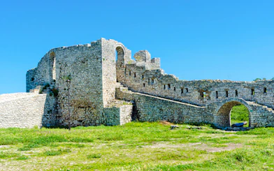 Berat Castle stone walls and archway under a clear blue sky in Albania.